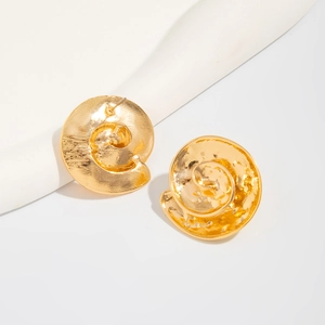 Close-up of golden spiral disc earrings featuring a vintage hammered metal texture