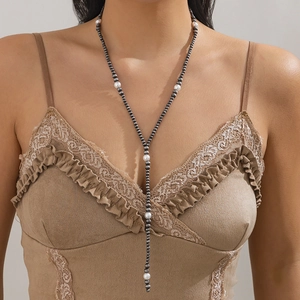 Detailed view of a vintage long Y-shaped necklace with grey beads and white pearls on a model