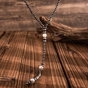 Close-up of vintage Y-shaped necklace with silver beads and pearls on wooden background