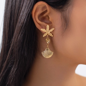 Golden starfish and shell drop earrings on a model, elegant ocean beach style jewelry