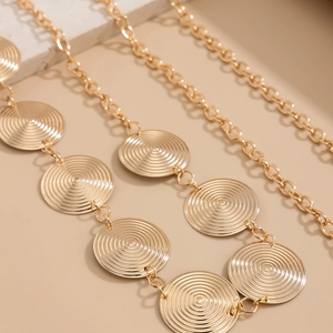 Gros plan d'une chaîne de taille dorée avec disques à texture spirale et anneaux o-link
