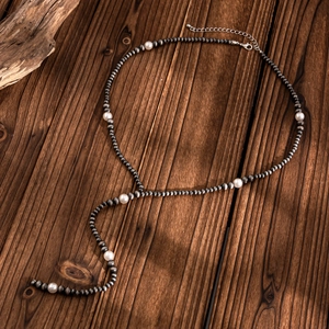 Vintage bohemian Y-shaped necklace with metal beads and faux pearls on wood background