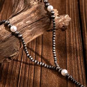 Detailed macro view of retro Y-shaped necklace with grey beads and large white pearls