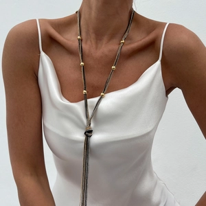 Detail of layered Y-shaped metallic fringe necklace with gold beads on satin dress