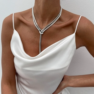 Silver snake bone chain necklace featuring a unique knotted Y-shape design on silk dress