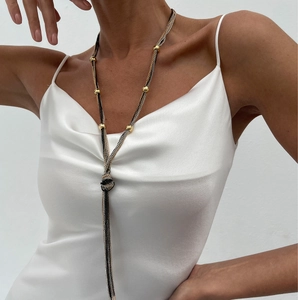 Close-up of minimalist layered Y-shape lariat necklace with metallic tassels and gold beads
