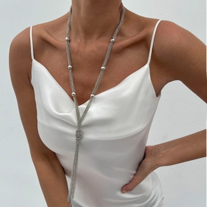 Close-up of a silver Y-shaped layered tassel necklace with metallic beads on a model