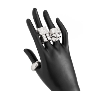 Close-up of four silver metal rings with geometric textures and rhinestones on black model hand