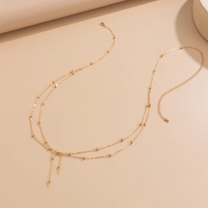 Close-up of golden double-layer body chain with delicate beads and tassel details