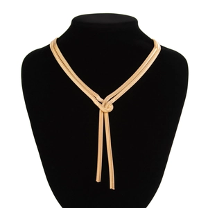 Detailed view of gold Y-shaped snake bone necklace on a black velvet neck model