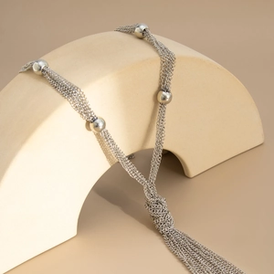 Silver multi-layer tassel necklace with round beads on a minimalist beige arch display