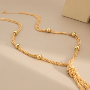 Detailed close-up of a layered gold Y-necklace featuring metallic beads and elegant tassels