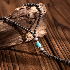 Vintage Y-shaped beaded necklace with blue turquoise bead on textured wood surface