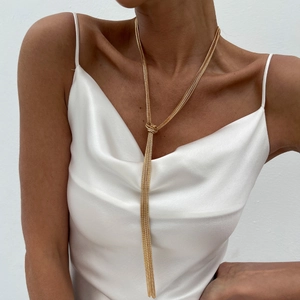 Close-up of golden multi-layer tassel necklace with knot design on white satin dress