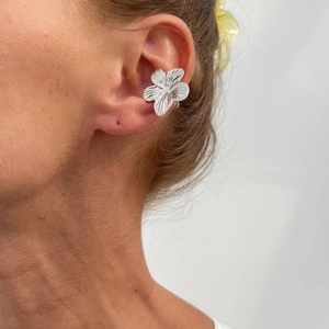 Gedetailleerde close-up van een zilveren bloem oormanchet met getextureerde blaadjes