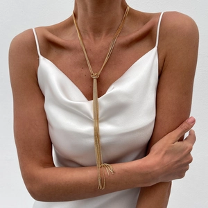 Detail view of a gold Y-shaped fringe necklace featuring an elegant central knot design