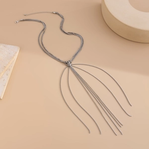 Close-up of silver multilayer tassel necklace with a stylish knot on minimalist background