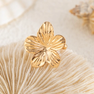 Detailed macro view of golden five-petal flower earring with radial textures on white background