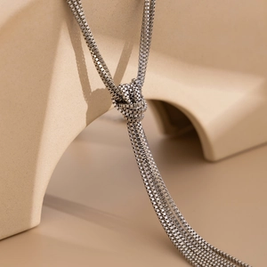 Macro detail of multi-strand silver metal chain necklace with tassel knot design