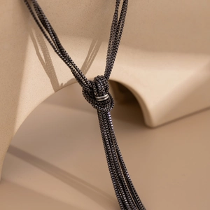 Close-up of black multi-layered box chain necklace with elegant knot and silver ring detail