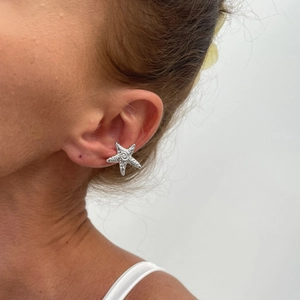Silver starfish earring detail on model with textured grain and spiral center pattern