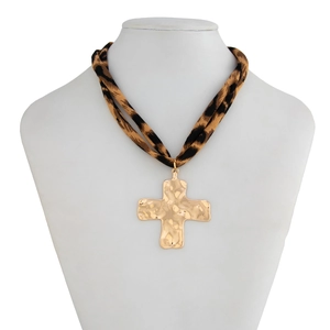 Close-up of a large gold hammered cross pendant with a double leopard print fabric cord