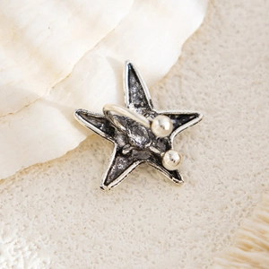 Macro detail of vintage silver starfish clip earring back on a shell and sand background