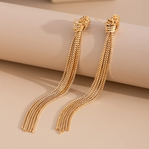 Close-up of elegant gold tassel earrings with intricate metal knot and box chains