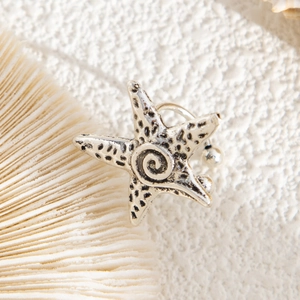 Detailed close-up of a silver starfish ear cuff with textured surface and spiral center