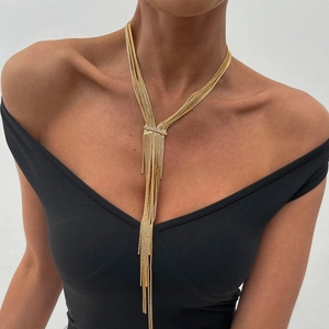 Detail of layered gold tassel necklace with zircon slider on black V-neck outfit