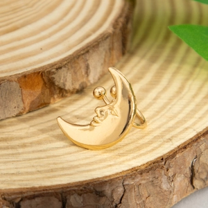 Artistic golden crescent moon earrings with face detail on a rustic wood background