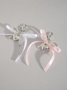 Détail de charmants bijoux de sac à nœud avec pendentifs cœur et perles tissées