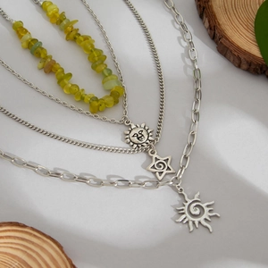 Détail d'un collier argenté multi-rangs avec pierres vertes et breloques étoiles