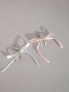Détail de porte-clés à nœud en ruban rose et blanc avec pendentifs cœurs et perles