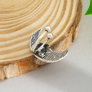 Detail of silver crescent moon open ring with textured stripes on wood background