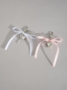 Détail de pendentifs en cœur avec des nœuds en ruban rose et blanc sur porte-clés argent