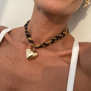 Macro detail of leopard print choker with a large polished gold heart pendant