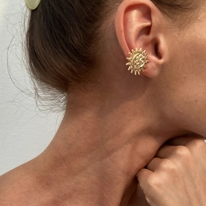 Vintage golden sun earrings with relief face design worn by a model in a close-up