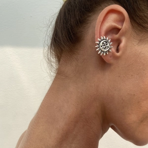 Close-up of silver celestial sun and moon relief ear cuff on a model's ear