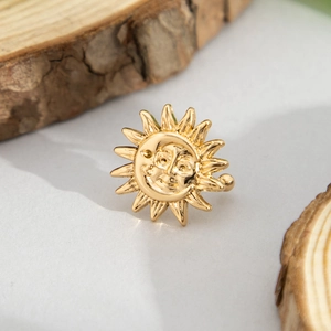 Macro shot of a golden sun face earring on a natural wooden slice with a warm artistic feel