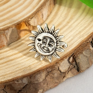 Macro detail of antique silver sun and moon face relief on a bohemian earring cuff