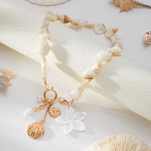 Detailansicht der Muschel-Halskette mit goldenen Anhängern und großer weißer Blüte