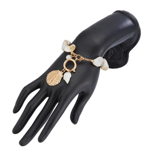Detail eines Meeresstil-Goldarmbands mit natürlichen Muscheln und Perle an einem Handmodell