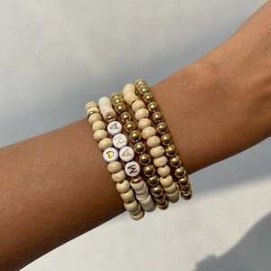 Detail of bohemian stackable bracelets featuring wood beads and Mama letter charms