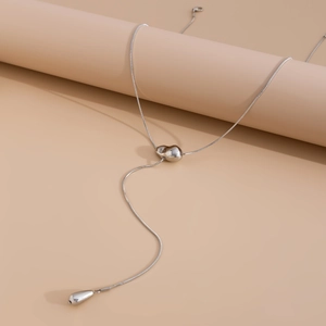 Macro detail of silver snake chain necklace featuring a minimalist teardrop pendant