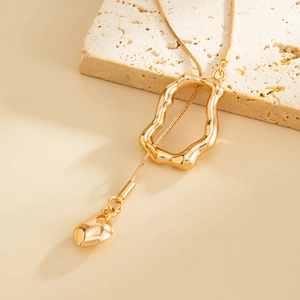 Detail of irregular hollow wave pendant and drop charm on golden snake chain