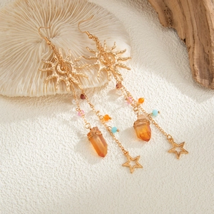 Details von Boho-Ohrringen in Gold mit bunten Perlen und Kristallen auf einem Korallentablett
