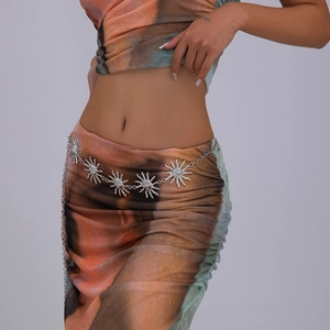 Detail of silver sun-shaped metal waist chain charms on bohemian print dress