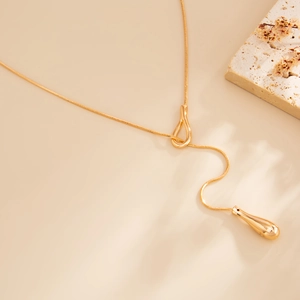 Detail of a minimalist gold snake chain necklace with a polished teardrop pendant