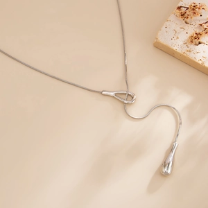 Detail of silver snake chain necklace featuring intertwined ring clasp and teardrop pendant